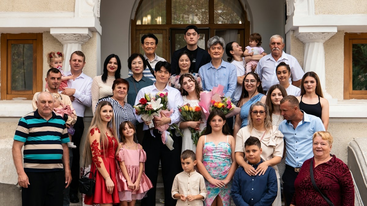 A large family group posing on stone steps in front of a building